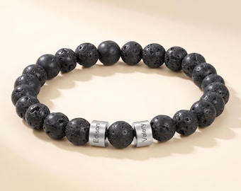 May include: A beaded bracelet composed of round, porous black lava stone beads. The bracelet features two cylindrical silver-toned metal spacers, each engraved with a name, with the name Edison on one and the name Valery on the other.