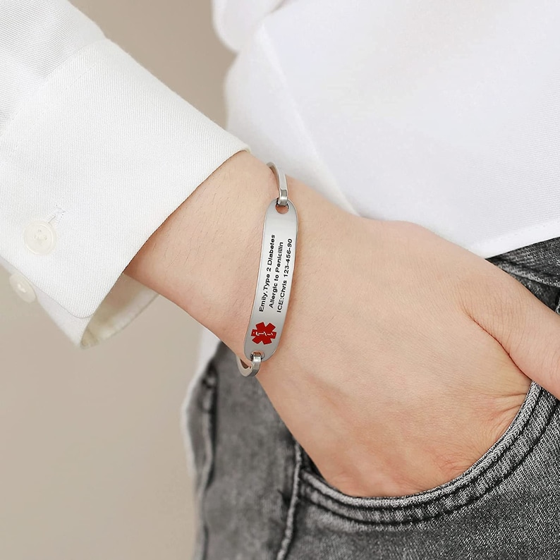 May include: A silver medical ID bracelet with a red medical symbol. The bracelet has the text "Emily, Type 2 Diabetes, Allergic to Penicillin, ICE: Chris 123-456-00" engraved on it.