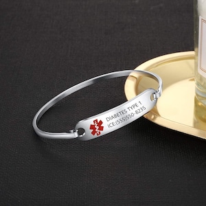 May include: Silver medical alert bracelet with a red medical symbol and the text "DIABETES TYPE 1 ICE:(555)550-8235".