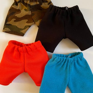 May include: Four pairs of shorts in different colors: camouflage, black, orange, and blue. The shorts are made of a soft, stretchy fabric and have an elastic waistband.