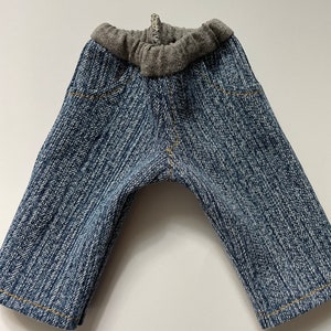 Può includere: Un paio di pantaloni di jeans blu con elastico in vita grigio.