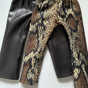May include: Two pairs of leggings, one black with a shiny finish and one brown and black with a snake print.