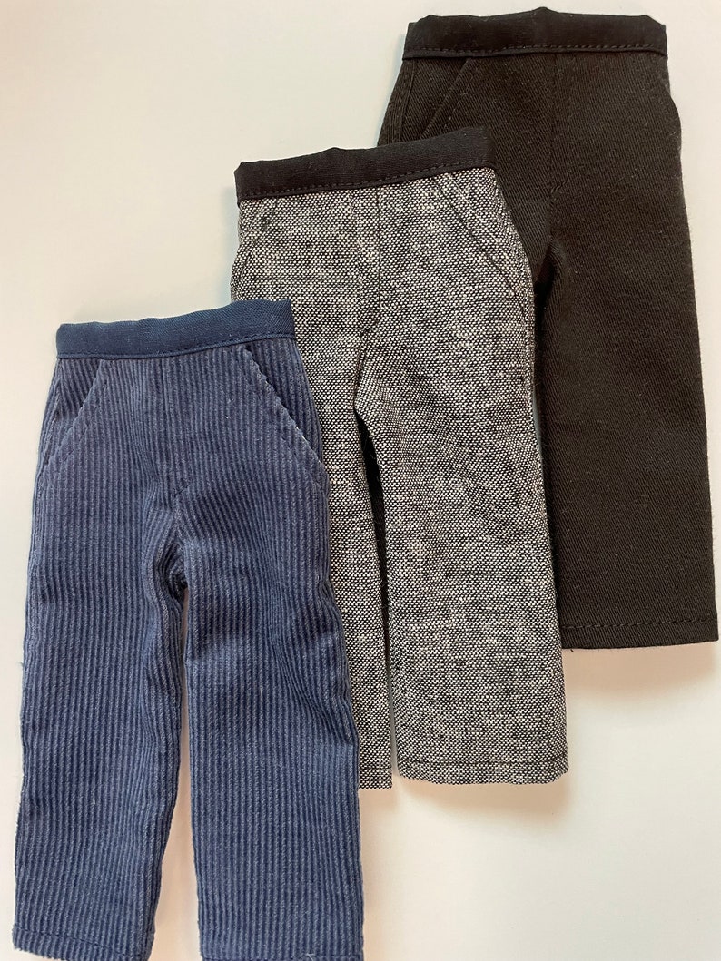 May include: Three pairs of pants in different fabrics and colors. The pants on the left are blue corduroy, the middle pants are gray tweed, and the pants on the right are black.