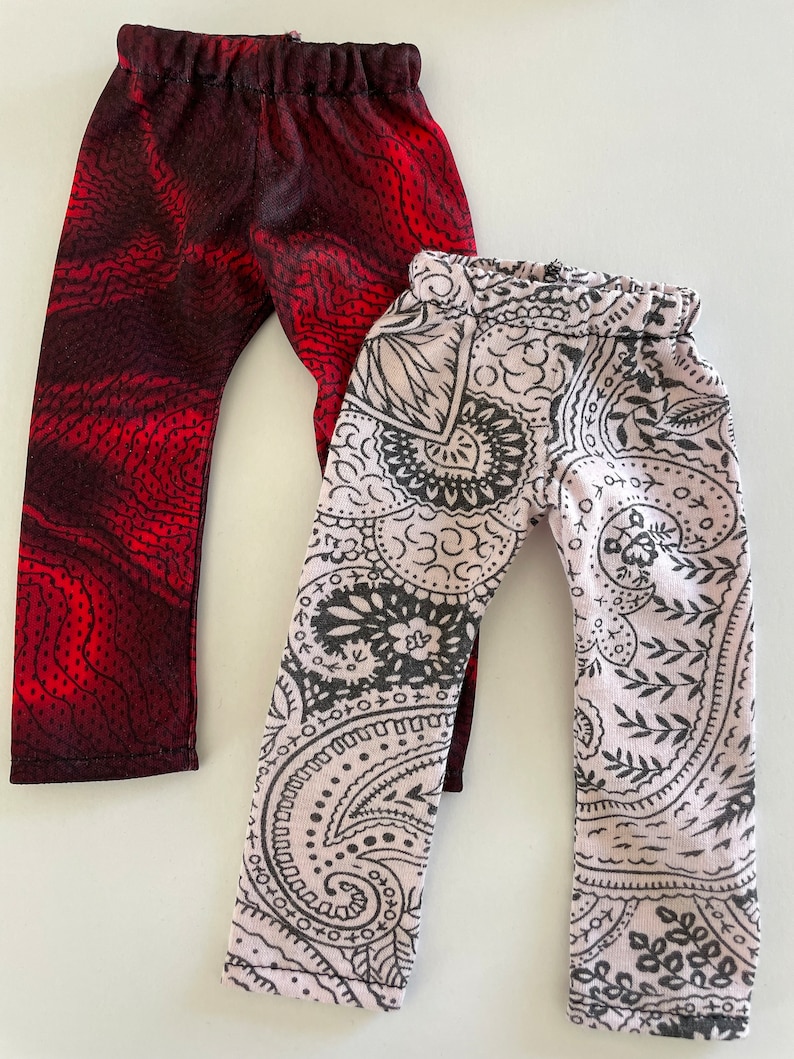 May include: Two pairs of leggings, one with a red and black swirl pattern and the other with a black and white paisley pattern.