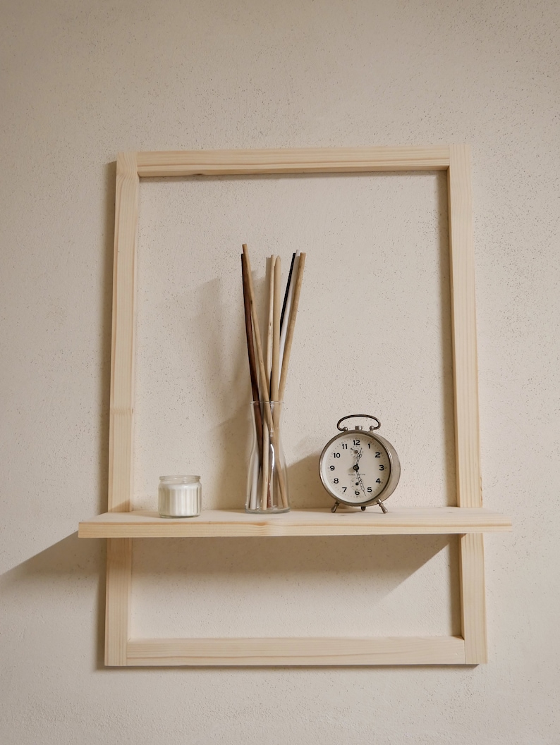 Puede incluir: Una estanter&iacute;a de madera con una vela blanca, un jarr&oacute;n de palitos y un reloj despertador vintage. La estanter&iacute;a est&aacute; unida a un marco de madera.