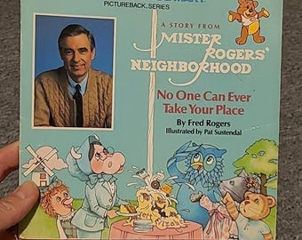 May include: A softcover children's book titled A Story From Mister Rogers' Neighborhood: No One Can Ever Take Your Place by Fred Rogers. The light blue cover features a photo of Fred Rogers and colorful illustrations of various characters.