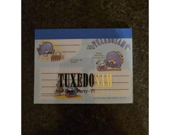 May include: A rectangular notepad with a blue top border featuring Tuxedo Sam characters. The text reads Tuxedo Sam, Since 1979, and Helpful Home Party-Planning Advice. The paper includes illustrations of the blue penguin character.