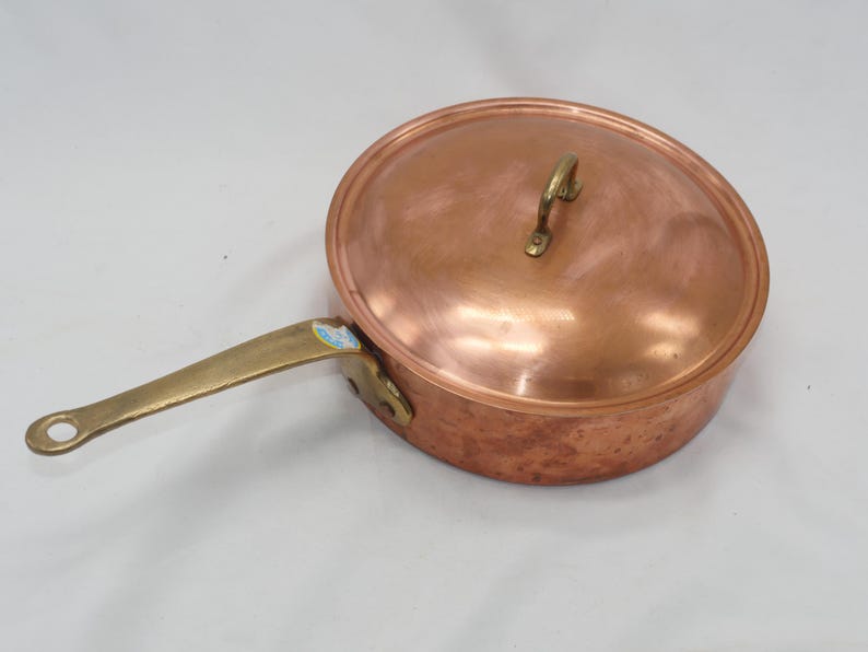 May include: A copper saucepan with a brass handle and a lid. The saucepan has a hammered finish.