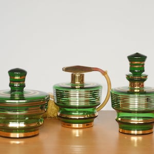 May include: A set of three vintage glass perfume bottles with gold accents. The bottles are green and have a striped design.