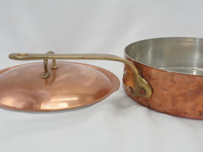 May include: Copper saucepan with a lid and brass handle. The saucepan has a hammered finish and the lid has a brass knob.