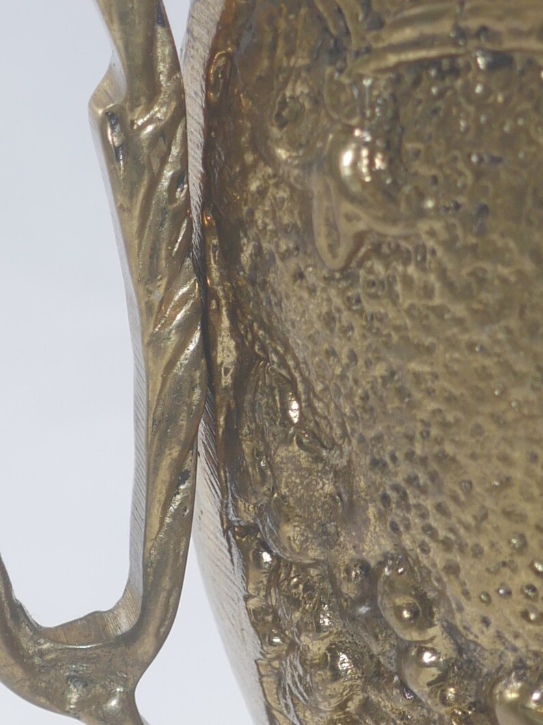 May include: A brass pitcher with a detailed design featuring a textured surface and a handle with a twisted design.