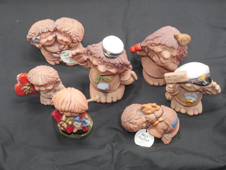 Pu&ograve; includere: Una collezione di sette piccole figurine in ceramica dipinte a mano. Le figurine sono tutte diverse, ma hanno tutte uno stile fantasioso e caricaturale. Alcune delle figurine tengono oggetti, come un cuore, una lumaca e un cartello che dice "En Vad Jag Arbra".