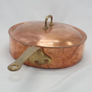 May include: A copper saucepan with a brass handle and lid. The saucepan has a hammered finish and is in good condition.