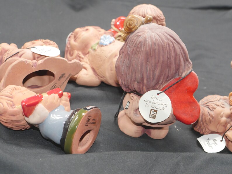 Pu&ograve; includere: Una collezione di cinque figurine in ceramica, ognuna con un design unico. Le figurine sono dipinte in vari colori, tra cui rosso, blu e marrone. Le figurine sono tutte in posizione seduta e guardano in direzioni diverse. Le figurine sono realizzate dalla societ&agrave; "JIE-Keramik" e sono progettate da Eva Jarenskog.
