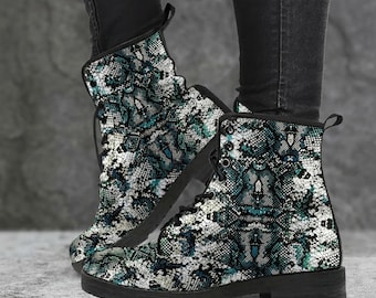 May include: A pair of ankle boots with a snakeskin pattern in shades of teal, white, and black. The boots have a lace-up design, a rounded toe, and a black sole. The boots are worn with black jeans.