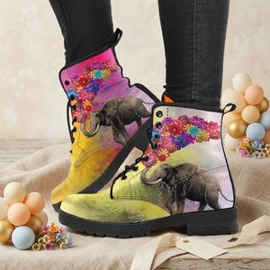 May include: A pair of colorful combat boots featuring an elephant design. The boots have a black sole and laces, with a vibrant floral and watercolor background. The elephant is depicted in a realistic style, adding a touch of nature to the footwear.