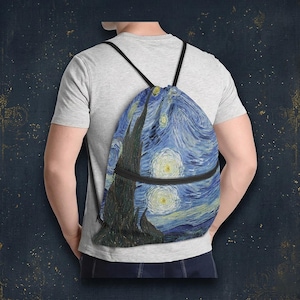 Op de afbeelding: Blauwe rugzak met trekkoord met een print van Van Goghs schilderij "De Sterrennacht". De tas heeft zwarte trekkoorden en een zwarte rits. Het kunstwerk toont wervelende blauwe luchten, heldere sterren en een donkere boom.