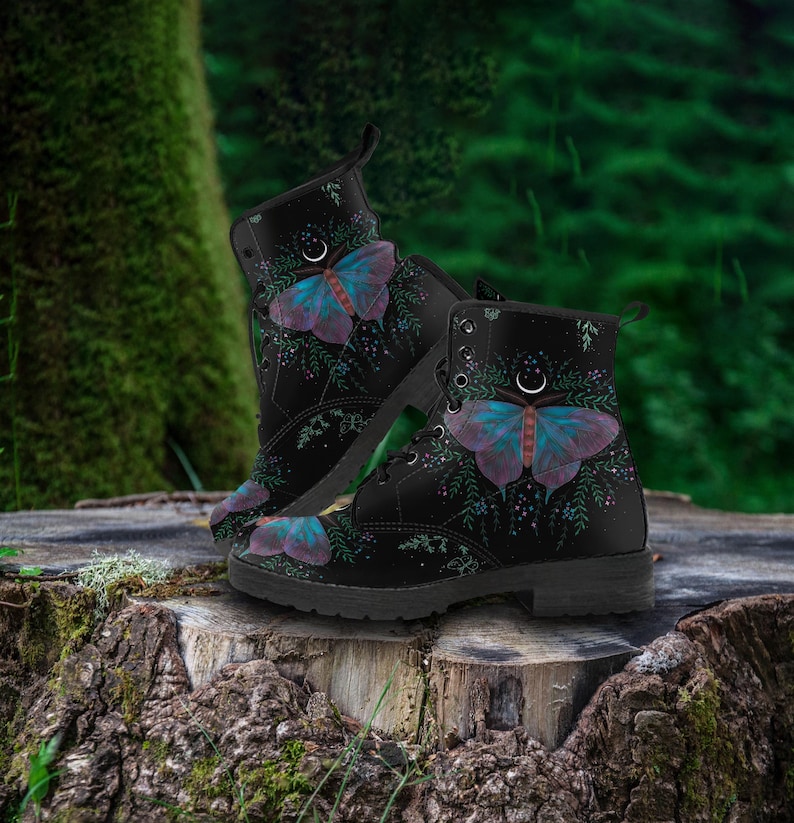 Pode incluir: Botas de combate pretas com um design de borboleta em roxo e azul-petr&oacute;leo. As botas t&ecirc;m fecho de atacadores e biqueira redonda. O design da borboleta &eacute; colocado sobre um fundo de folhagem verde e uma lua crescente. Altura: aprox. 25 cm.