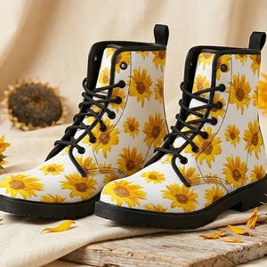May include: White combat boots featuring a yellow sunflower design. The boots have black laces, soles, and pull tabs. They are set on a wooden surface with a neutral backdrop.