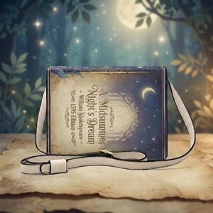 Könnte beinhalten: Eine Umhängetasche mit dem Cover-Design von William Shakespeares "A Midsummer Night's Dream". Die Tasche hat einen cremefarbenen Riemen und einen goldfarbenen Verschluss. Das Buchcover-Design zeigt einen Halbmond, Sterne und eine Waldszene.