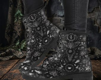 Op de afbeelding: Zwarte combat boots met een gedetailleerd wit grafisch patroon met motten, schedels en andere mystieke symbolen. De laarzen hebben een vetersluiting en een stevige zool, perfect voor een gothic of alternatieve stijl.