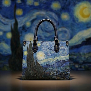 May include: A tote bag featuring a print of Vincent van Gogh's "The Starry Night." The bag has a rectangular shape with a dark blue handle and gold-colored hardware. The artwork depicts a swirling night sky with a village and cypress tree.