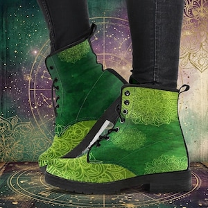 Könnte beinhalten: Grüne Combat-Stiefel mit Mandala-Muster. Die Stiefel haben einen Schnürverschluss, einen seitlichen Reißverschluss und eine schwarze Sohle. Das Mandala-Muster ist in einem helleren Grünton gehalten und kontrastiert mit dem dunkleren Grün. Ca. 20 cm hoch.
