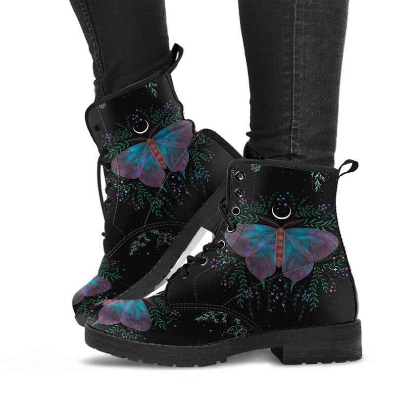 Pode incluir: Botas de combate pretas com um design de borboleta vibrante em tons de azul, roxo e vermelho. As botas t&ecirc;m fecho de atacadores e um pequeno salto. A borboleta &eacute; rodeada por folhagem verde e pequenos detalhes florais.
