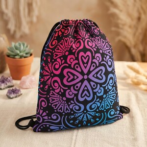 Può includere: Borsa con coulisse nera con un design simmetrico vibrante nei toni del rosa, viola e blu. Il motivo presenta motivi a cuore e floreali. La borsa è realizzata in materiale morbido e ha una chiusura con coulisse nera.