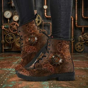May include: Brown ankle boots with a steampunk gear design. The boots have a lace-up closure, a black sole, and a repeating pattern of bronze-coloured gears and cogs. The boots are worn with black trousers.