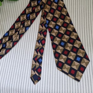May include: A brown, blue, and red geometric patterned tie. The tie has a dark blue background with a pattern of triangles and squares.
