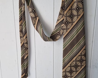 May include: A brown, green, and beige patterned tie with a geometric design. The tie is hanging on a copper pipe.