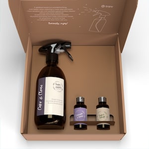 May include: A brown cardboard box containing a large amber glass spray bottle labelled Care & Clean, alongside two smaller amber glass bottles labelled Lavender & Lemon and Sage & Orange. The box lid features text and a line drawing of a spray bottle.