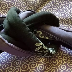 May include: A close-up of a purple and black fabric knot tied in a complex pattern. The fabric has a white floral design.