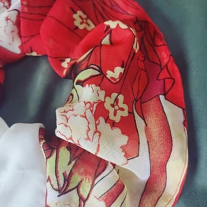 May include: Red and white floral print fabric with a ruffled edge. The fabric has a sheer texture and is perfect for crafting projects.