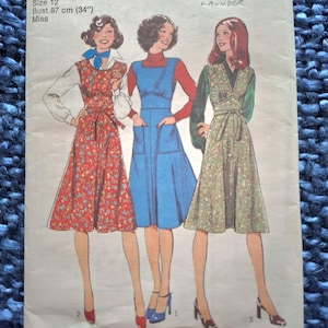 Puede incluir: Patrón de costura vintage con tres diseños de vestidos. El patrón muestra un vestido floral rojo, un vestido peto azul y un vestido floral verde. El patrón está etiquetado como "Style" e incluye información de tallas: Contorno de pecho 87 cm, Talla 12.