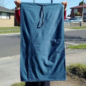 May include: A large, dark blue fabric rectangle with a single loop at the top. The fabric has a slight sheen and appears to be made of cotton.