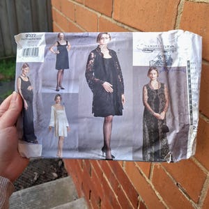 Może przedstawiać: Pakiet ze wzorem do szycia w stylu vintage z ilustracjami różnych wzorów sukienek. Opakowanie jest głównie szare i białe, ze zdjęciami sukienek w czerni i bieli. Widoczna jest nazwa marki "Lauren Sara". Opakowanie jest trzymane przez dłoń.