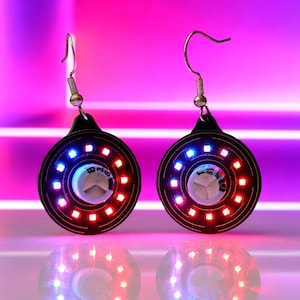 Pendientes con supercondensadores recargables y LED rojos y azules: joyería tecnológica para festivales de EDM.