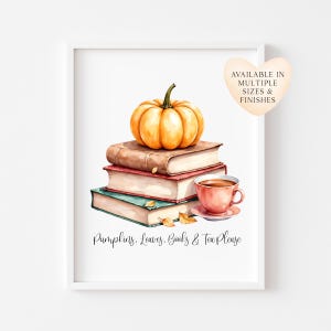 May include: A framed wall art print featuring a watercolour illustration of a stack of three books topped with an orange pumpkin and a pink teacup on a saucer. The text reads: Pumpkins, Leaves, Books & Tea Please. A heart-shaped tag says: AVAILABLE IN MULTIPLE SIZES & FINISHES.