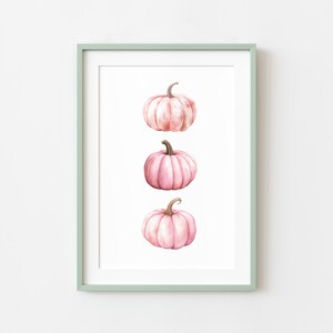 K&ouml;nnte beinhalten: Gerahmter Kunstdruck mit drei rosa Aquarellk&uuml;rbissen auf wei&szlig;em Hintergrund. Die K&uuml;rbisse haben braune Stiele. Der Rahmen ist hellgr&uuml;n.