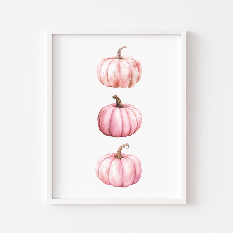 K&ouml;nnte beinhalten: Gerahmter Kunstdruck mit drei rosa Aquarellk&uuml;rbissen auf wei&szlig;em Hintergrund. Jeder K&uuml;rbis hat einen braunen Stiel. Die vertikale Anordnung ist schlicht und elegant, ideal f&uuml;r die Herbstdekoration.