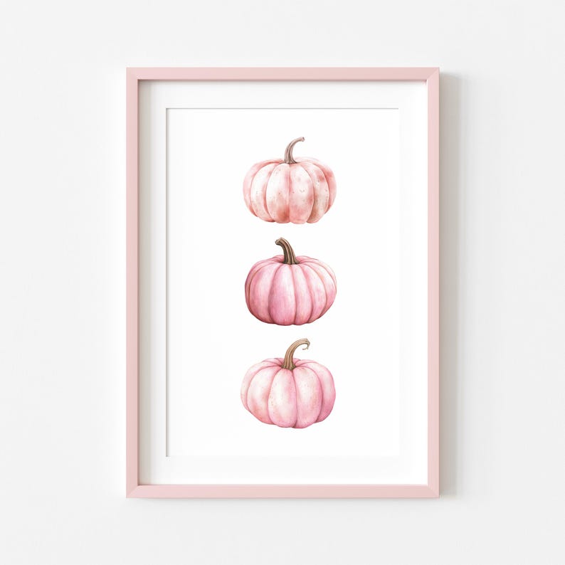 K&ouml;nnte beinhalten: Gerahmter Kunstdruck mit drei rosa Aquarellk&uuml;rbissen auf wei&szlig;em Hintergrund. Die K&uuml;rbisse haben braune Stiele. Der hellrosa Rahmen erg&auml;nzt die Illustration und schafft eine herbstliche Atmosph&auml;re.