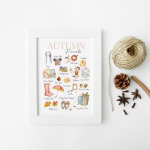 K&ouml;nnte beinhalten: Ein wei&szlig;er gerahmter Druck mit dem Text "AUTUMN Favourites" in braunen Buchstaben. Der Druck zeigt eine Aquarellillustration verschiedener Herbstartikel, darunter ein Schal, ein Hut, ein K&uuml;rbis, ein Buch, eine Decke, ein Paar Stiefel, ein Regenschirm, eine Tasse Kaffee, ein Honigglas, ein Korb mit &Auml;pfeln und ein Paar Hausschuhe.