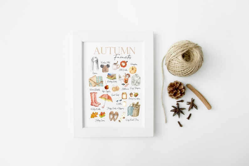 K&ouml;nnte beinhalten: Ein wei&szlig;er gerahmter Druck mit dem Text "AUTUMN Favourites" in braunen Buchstaben. Der Druck zeigt eine Aquarellillustration verschiedener Herbstartikel, darunter ein Schal, ein Hut, ein K&uuml;rbis, ein Buch, eine Decke, ein Paar Stiefel, ein Regenschirm, eine Tasse Kaffee, ein Honigglas, ein Korb mit &Auml;pfeln und ein Paar Hausschuhe.