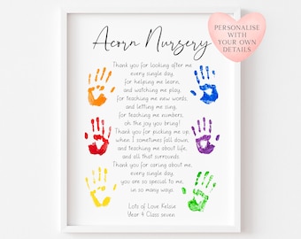 May include: A framed print with the text "Acorn Nursery" and a poem with colorful handprints. The print includes the text "Personalise with your own details" on a heart-shaped graphic. The bottom of the print reads "Lots of Love Kelsie Year 4 Class seven."