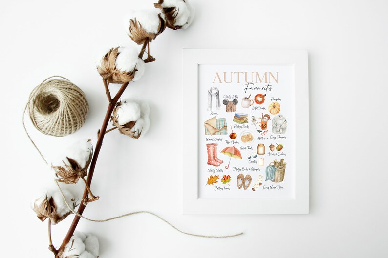 K&ouml;nnte beinhalten: Ein wei&szlig;er gerahmter Druck mit dem Text "AUTUMN Favourites" in braunen Buchstaben. Der Druck zeigt eine Sammlung von Aquarell-Illustrationen von Herbstgegenst&auml;nden, darunter ein K&uuml;rbis, Bl&auml;tter, Stiefel und eine Tasse hei&szlig;e Schokolade.