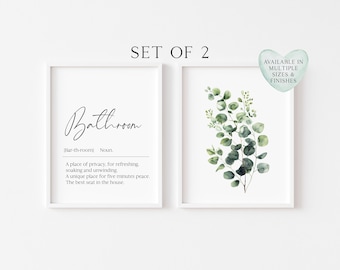 May include: A set of two framed wall art prints. The left print features the word Bathroom in script, its phonetic spelling, and a definition. The right print displays a watercolour illustration of green eucalyptus leaves on a white background.