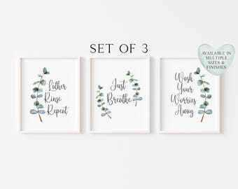 May include: A set of three white-framed wall art prints featuring watercolour eucalyptus branches and black text. The prints read Lather Rinse Repeat, Just Breathe, and Wash Your Worries Away. A heart-shaped badge states Available in Multiple Sizes & Finishes.