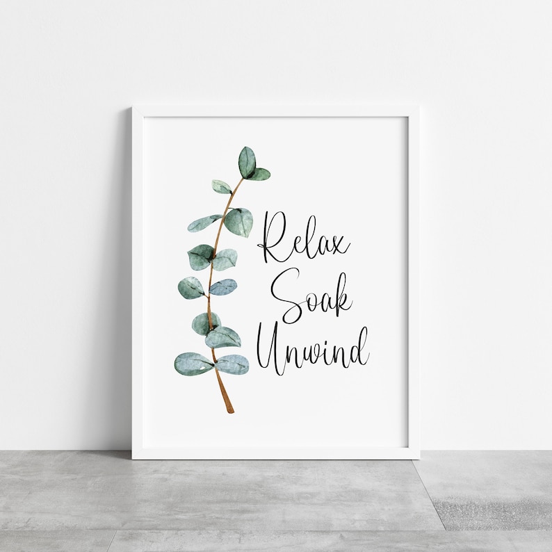 Puede incluir: Una impresi&oacute;n enmarcada en blanco con las palabras "Relax, Soak, Unwind" en escritura negra. Una ilustraci&oacute;n de acuarela de una rama de eucalipto con hojas verdes y verde azulado est&aacute; a la izquierda. El marco es blanco.
